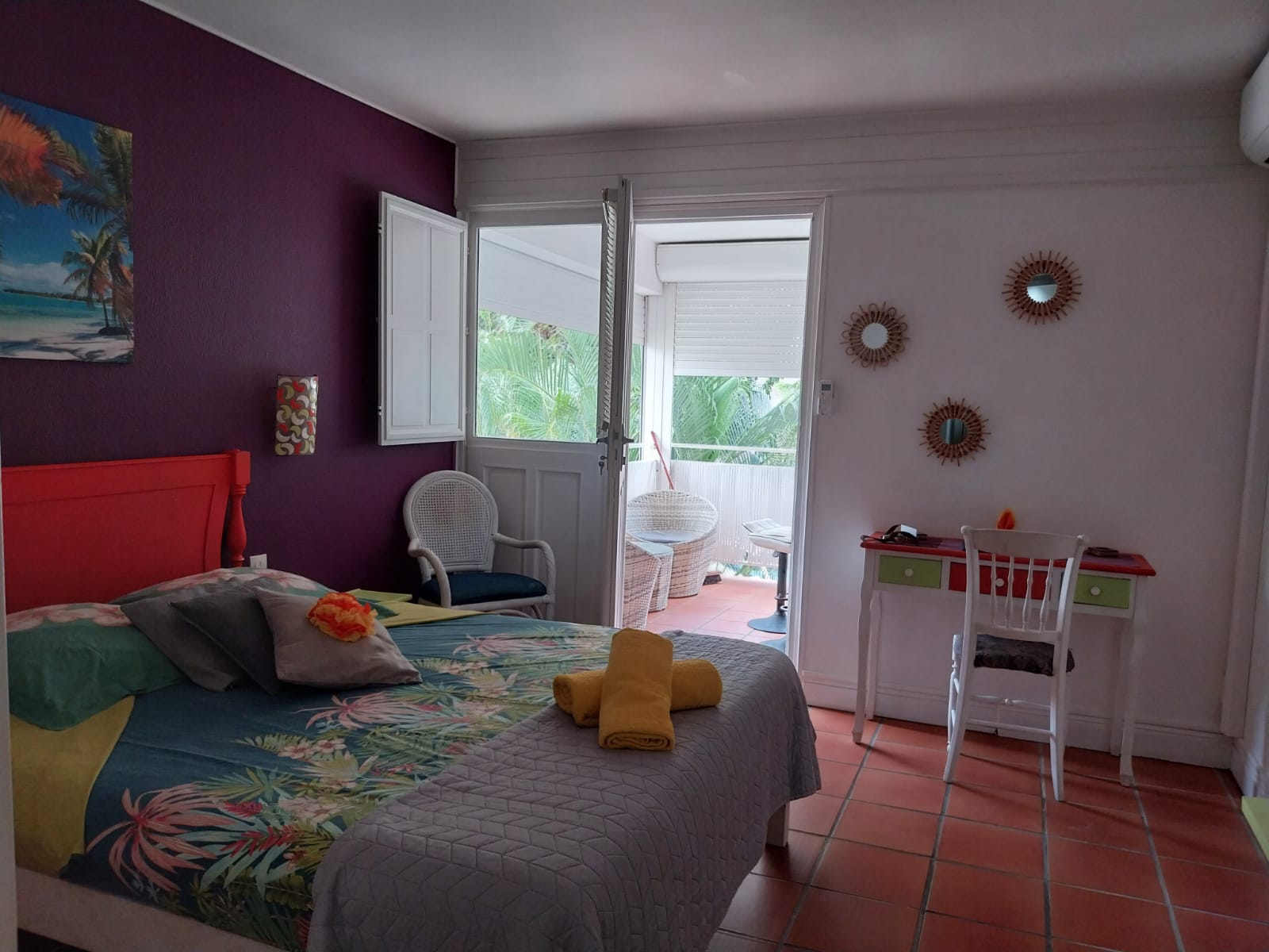 Chambre avec tête de lit rouge et mur violet, accès direct au balcon